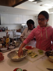 Imari and Olivia cover the vegetables in flour and egg to be cornmeal crusted.